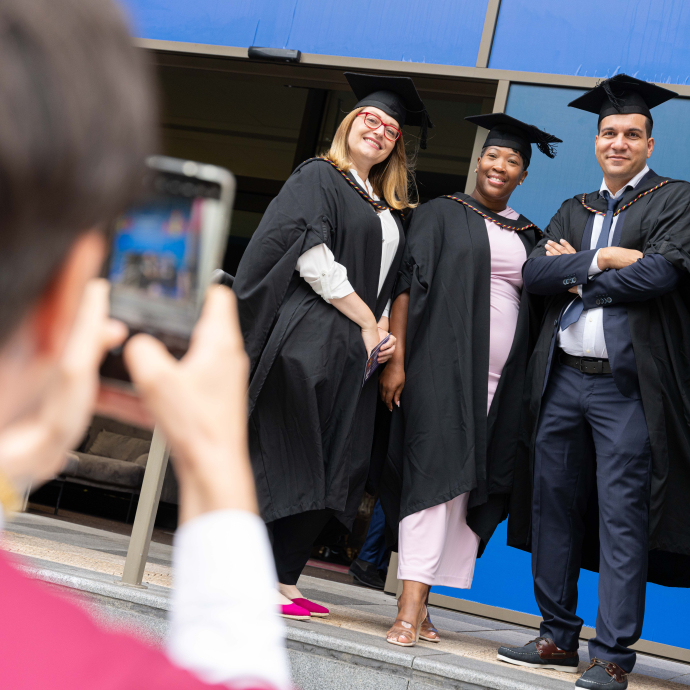 a person taking a photo of three graduates