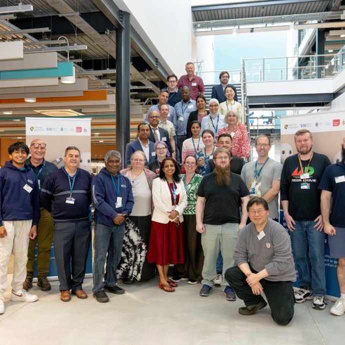 A large group of people standing in front of and on the staircase of a university building.