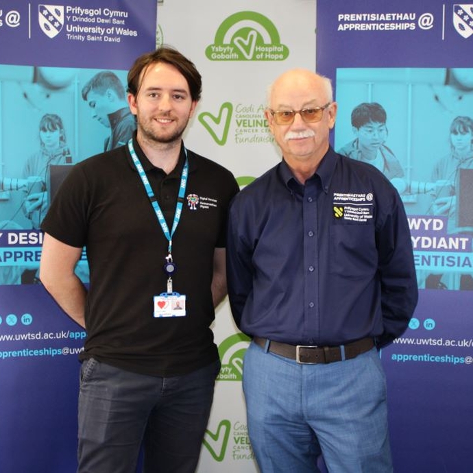 Two men in branded tops standing against a blue banner.