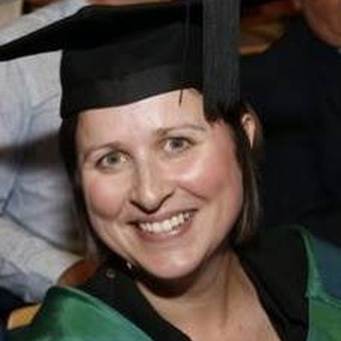 Senior Lecturer Angharad Lewis smiling in her cap and gown