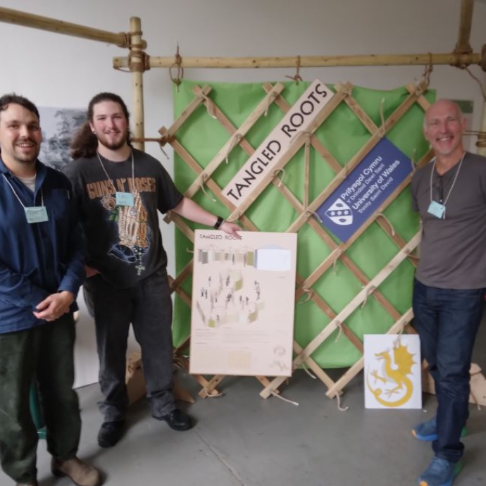 Two students and a lecturer standing beside their winning design.
