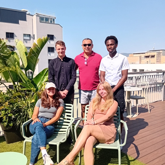 a group of students and lecturers sitting and standing outside 