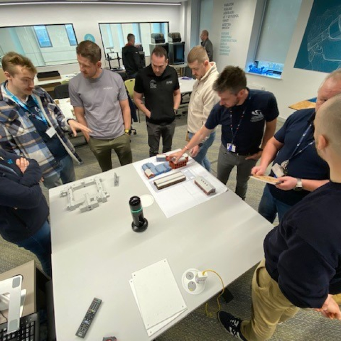 A group of people standing around a white table in a workshop.