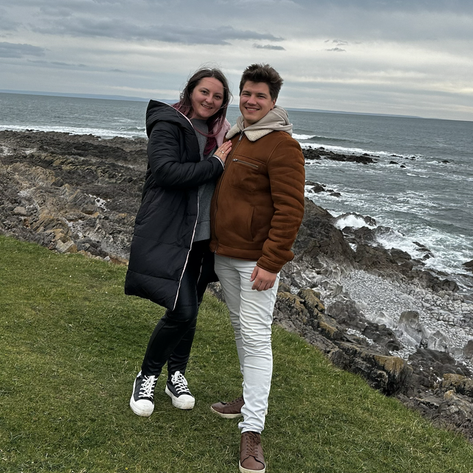 Lily and Ruslan standing on a cliff with the sea in the background