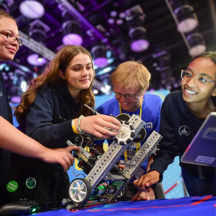 Three students and a lecturer involved in a robotics competition.