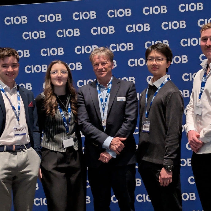 A group of smiling students standing proudly against a branded background.