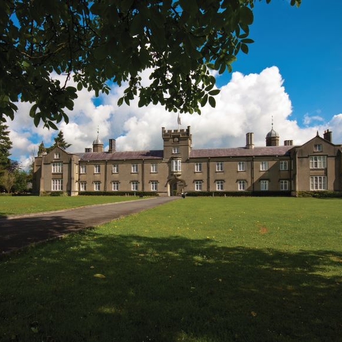 A historic building set against a bright blue sky with grass, partly in shadow at the front of the image.