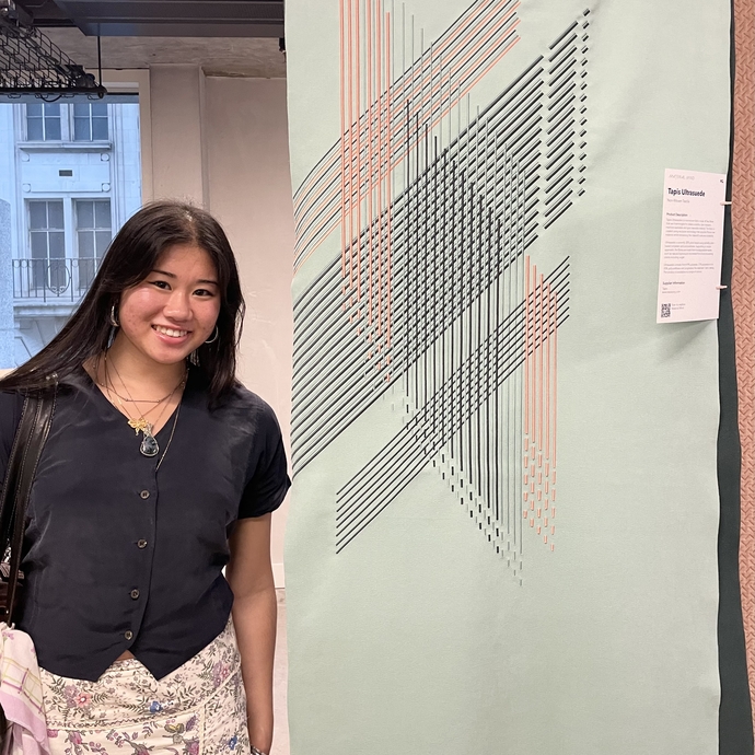 A girl smiling next to artwork on display