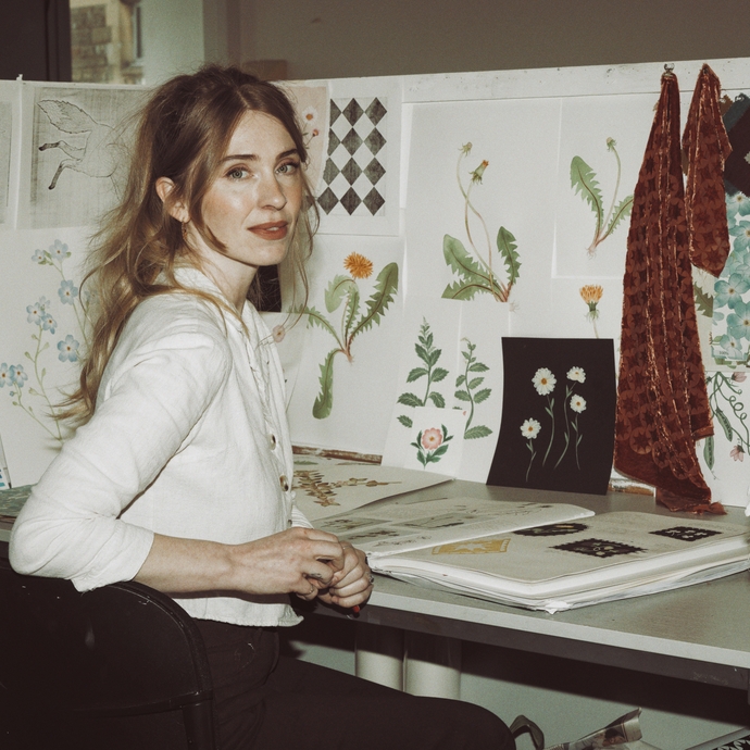 A person sitting on chair in front of desk with drawings of flowers in front of them