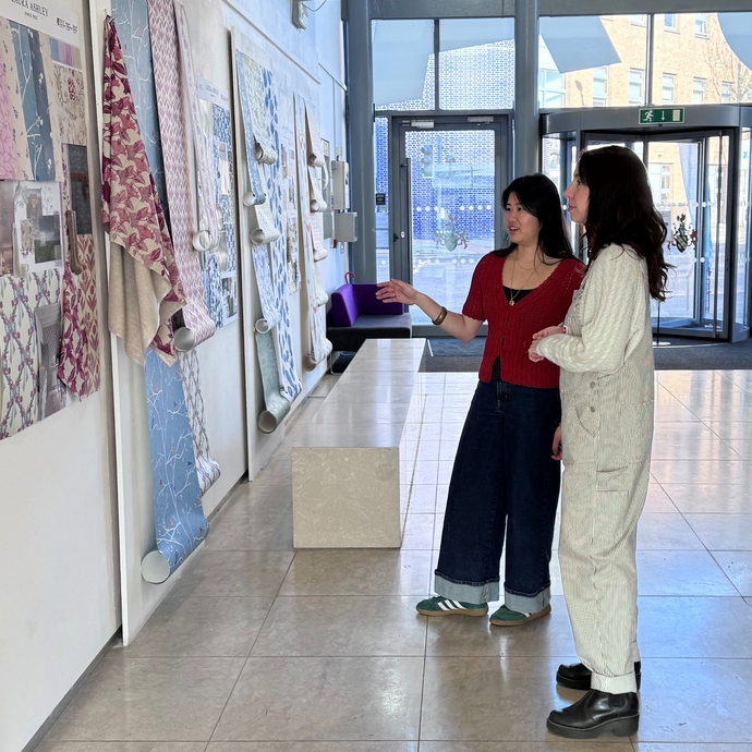 Two students viewing colourful art work on a wall.