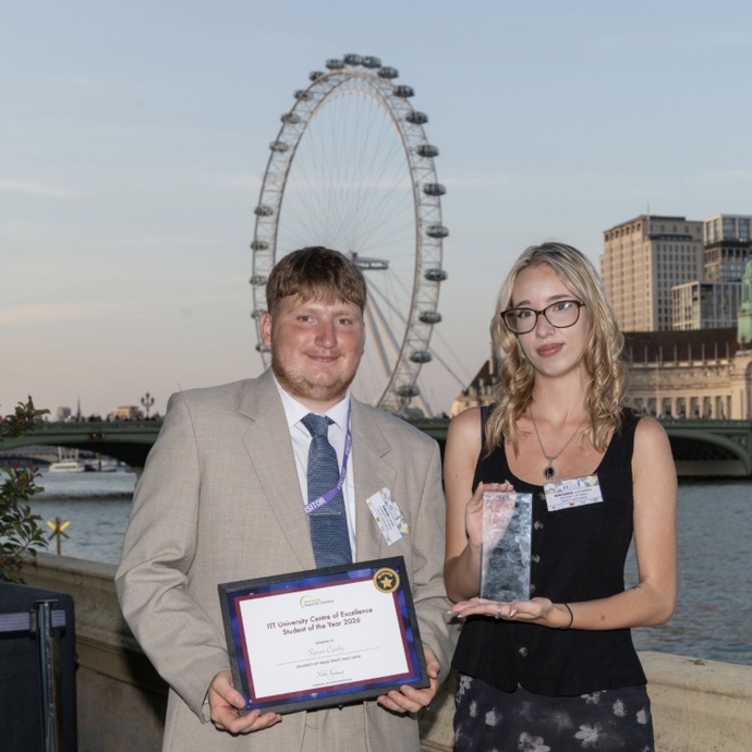 Two students standing on the terraces at the House of Commons in London, with the London eye in the background.