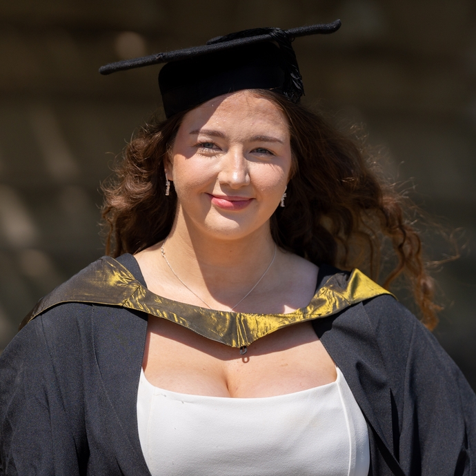A woman smiling for camera dressed in cap and gown