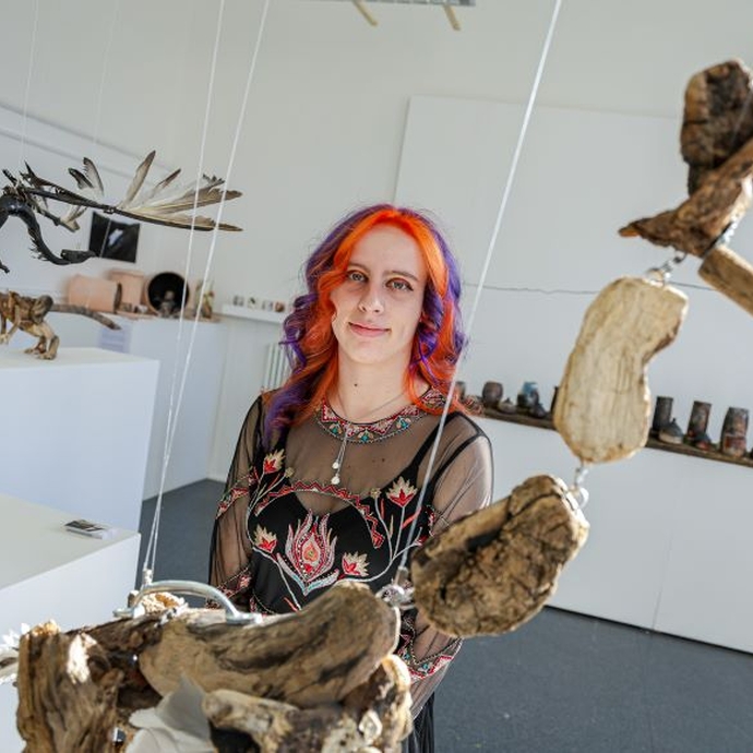 A student standing close to drift wood expressive forms.